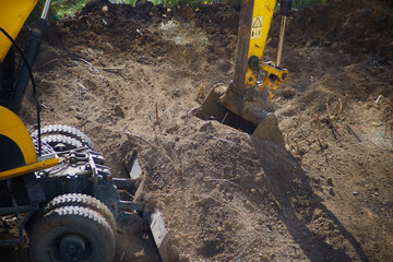 Powered excavator bucket in the ground at a construction site close-up