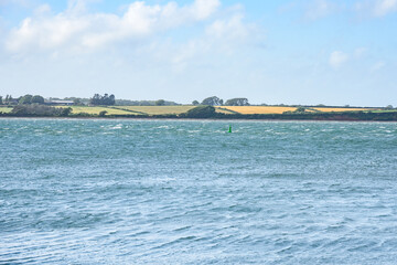 Obraz premium Agricultural fields along a windy coast on a clear summer day