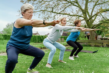 Active senior women doing squats outdoors in spring park fitness class