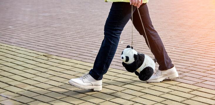 Stylish Woman with Adorable Panda Bag Strutting in Urban Setting, Trendy Street Fashion Scene