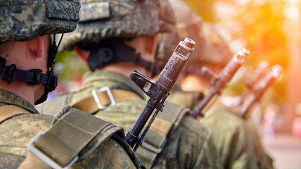 Brave soldier in camouflage uniform standing at attention with rifle on shoulder