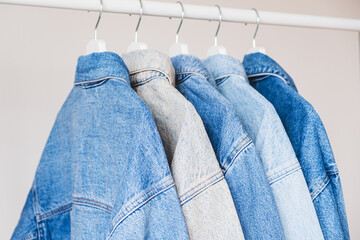 Blue denim jackets on hangers. Different shades of blue jeans color.