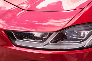 Headlight of luxury red car closeup