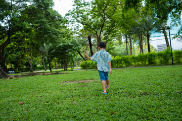 Fototapeta premium Happy asian preschool boy walking in green tropical tree forest in city park