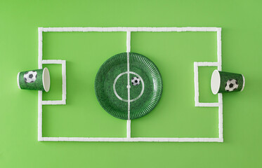 Football pitch or soccer field made with paper cups and plate and sugar cubes on light green background. Minimal sport or food concept. Creative football party composition. Flat lay, top of view. © Jakov Ilkoski