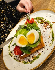 Delicious Belgian waffles with egg, with microgreens, avocado and vegetables in a plate, close-up. Delicious sandwich with egg. Ketogenic diet breakfast