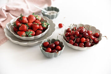 Fresh summer berries into bowls on white table. Summer food concept. Soft focus