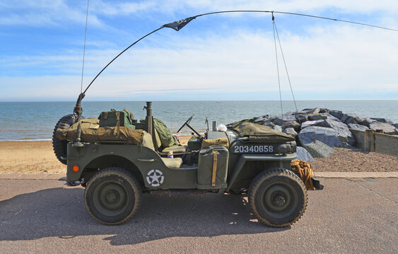 Classic 1942 Ford GPW Willys Jeep parked on seafront promenade beach and sea in background