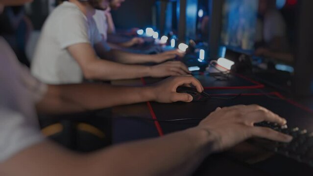Gamers play video game on PC at computer club, cyber sport tournament, professional E-sport championship. Gaming mouse RGB lighting keyboard on mat close up. Multiplayer online real-time strategy RTS