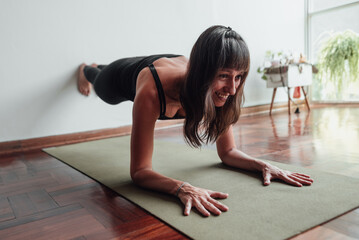 Happy woman taking care of her well-being by practicing yoga at home.