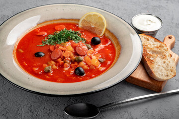 Smoked meat and sausage soup with tomatoes, olives and herbs ser