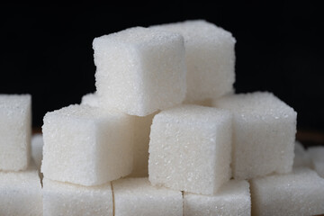 Pile of refined sugar cubes dark background.