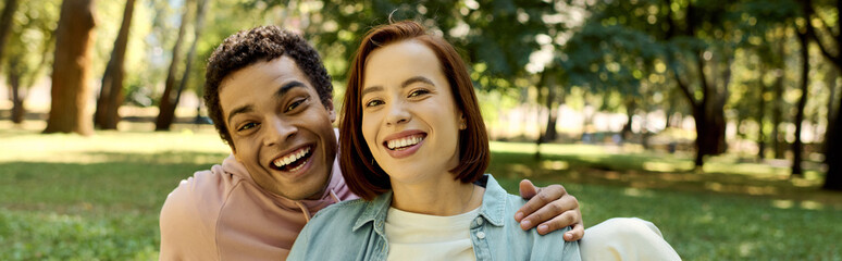 A diverse, loving couple in vibrant attire enjoying a relaxing moment together in a grassy park.