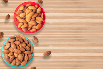 California almonds in two small bowls isolated on wooden table.