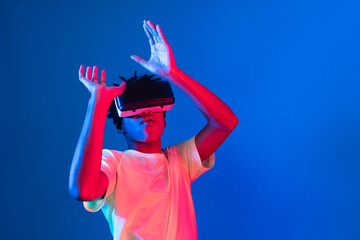 Young African American basketball gaming player wearing VR bouncing pose on blue pink neon light...
