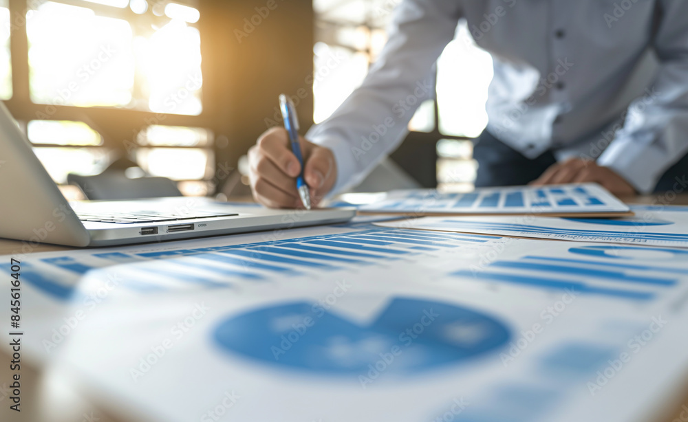Poster a person working on financial documents with charts and graphs on a desk, emphasizing analysis and b