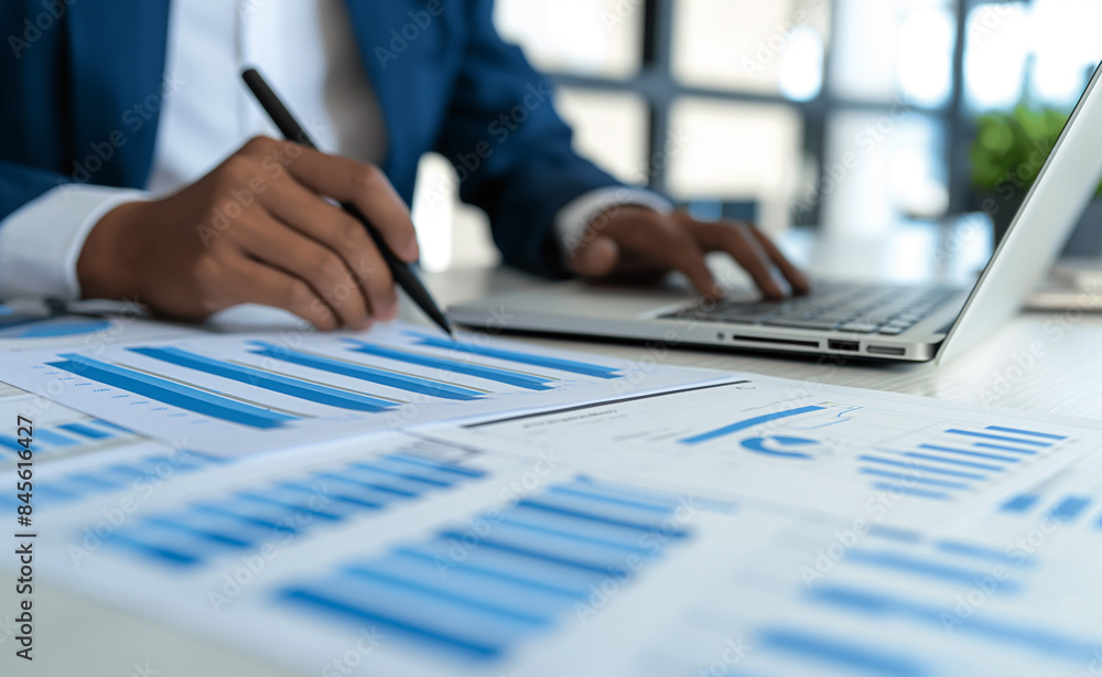 Poster a person working on financial documents with charts and graphs on a desk, emphasizing analysis and b