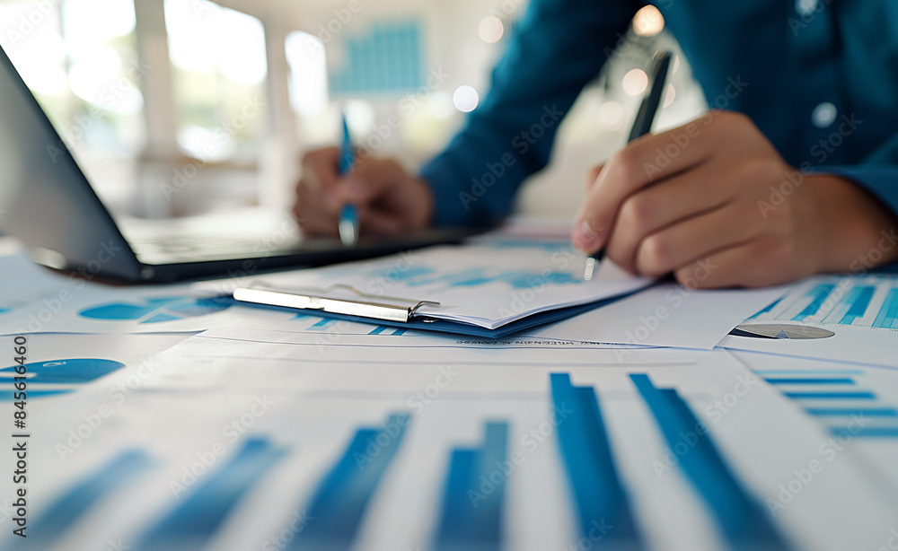 Poster a person working on financial documents with charts and graphs on a desk, emphasizing analysis and b