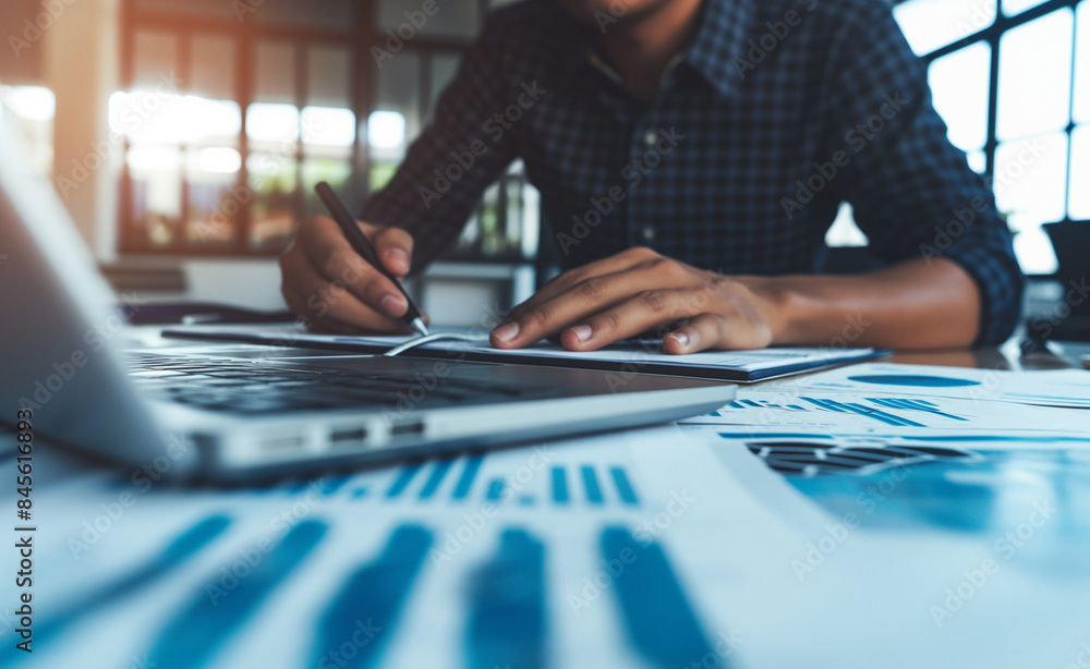 Poster a person in a suit analyzing business charts and graphs spread out on a table, indicating data revie