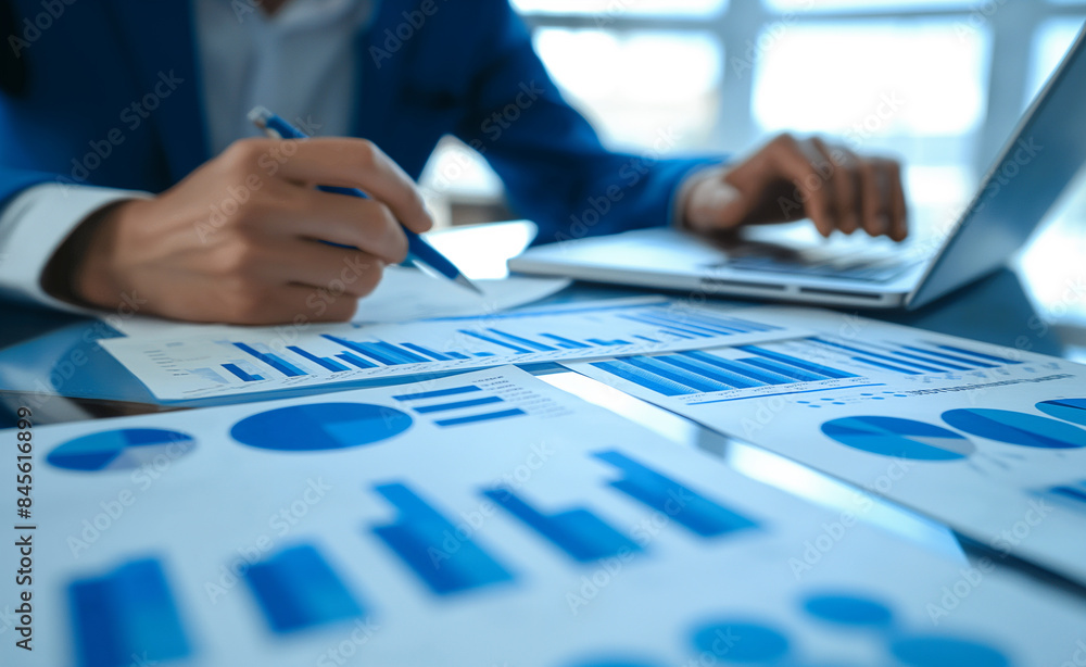 Poster a person in a suit analyzing business charts and graphs spread out on a table, indicating data revie