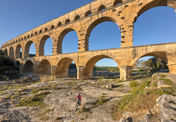 senior woman mountainbiking with her e bike below the famous roman aqueduct of Pont du Gard near...