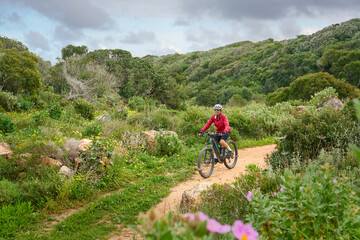 happy active senior woman cycling on the the rocky cliffs of the Vicentina coast of  Algarve,...