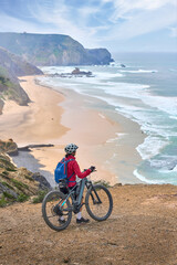 Fototapeta premium happy active senior woman cycling on the the rocky cliffs of the Vicentina coast of Algarve, Portugal near Sagres and Vila do Bispo 