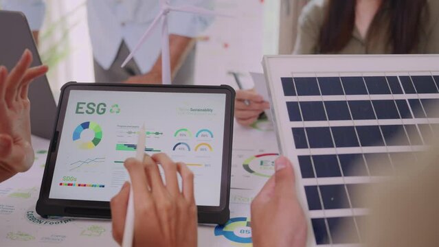 diversity team discussion focused on ESG (environment,social,governance)  focus on esg rating on laptop in a sustainable green office