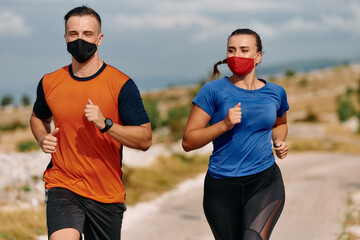 Couple running in nature at morning wearing protective face masks