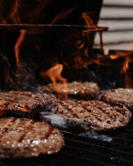 hamburgers cooking on the grill with open flame