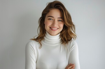 Obraz premium Woman With Brown Hair Smiling in White Turtleneck Against White Wall