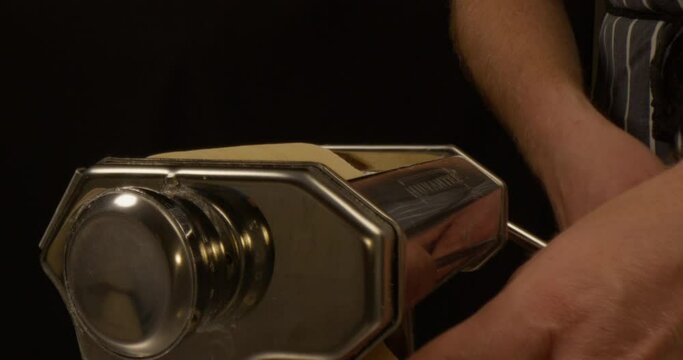 Male hand making lasagne sheets in a pasta machine