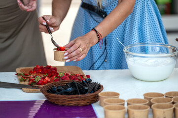 Woman adding strawberries to dessert. Shallow depth of feld