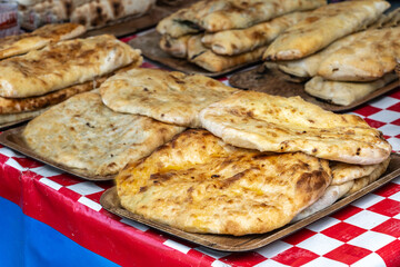 Georgian khachapuri set, flatbreads with cheese, spinach, mushrooms at street market. Golden brown khachapuri