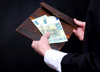 Unrecognizable business woman holds euro money and a leather wallet