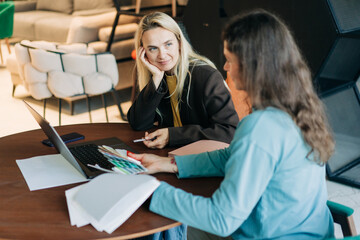 Female colleagues working on a design project while sitting at their office desk.