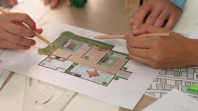 Professional engineer team discussion about house design on meeting table with architectural equipment and building blueprint scatter around at modern office. Focus on hand. Closeup. Delineation.