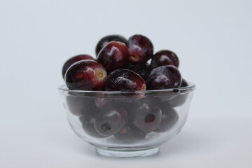 Dark purple or black grapes, off the stem, or without stalk, inside transparent bowl, isolated on white background