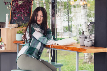 A young beautiful girl sits in a cafe and drinks coffee.