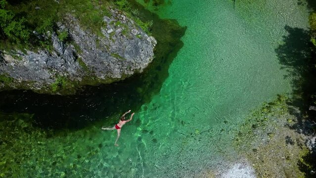 Female Tourist hiker Solo Swimming in an Emerald Green Mountain River Drone View 4K Video