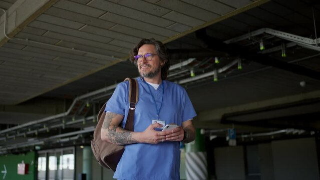 Video of handsome doctor in uniform outdoors, scrolling phone. Work-life balance of healthcare worker.