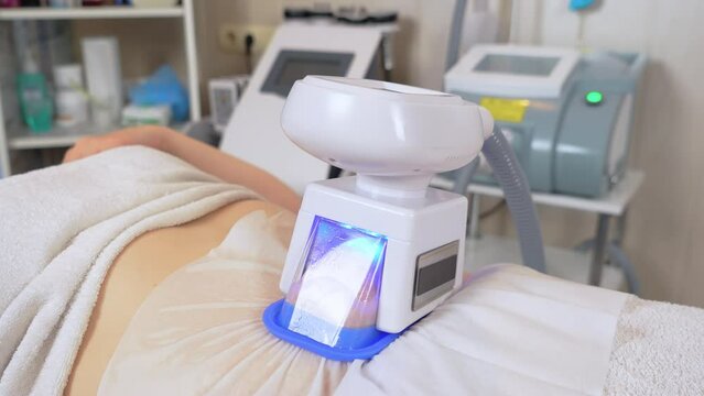 Large woman client utilizes hardware based cosmetology methods to sculpt her body to perfection at beauty salon. Close up of machine cryolipolysis fat treatment procedure of young woman