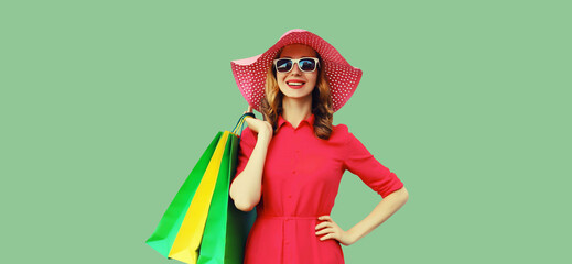 Portrait beautiful happy smiling young woman model posing with colorful shopping bags in summer hat
