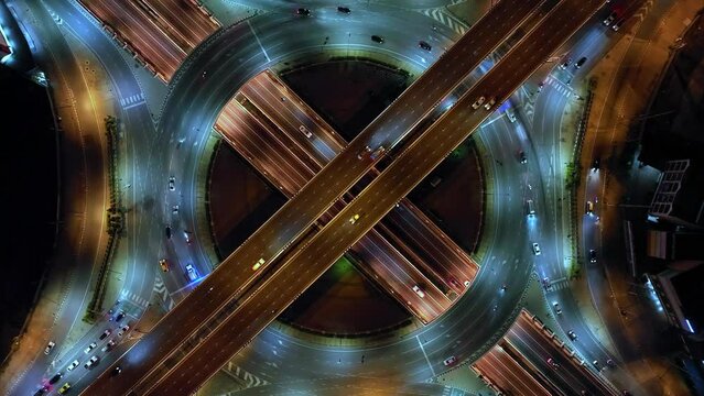 Financial technology, energy power, beautiful top view time-lapse of car traffic at roundabout lane and buildings. 4K drone aerial zoom out. Urban cityscape concept or abstract of advanced innovation.