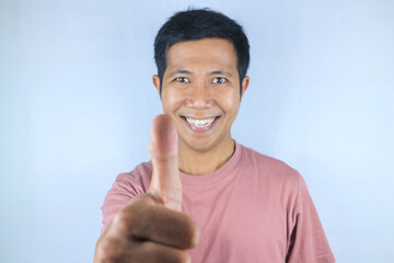 Funny face expression young asian man looking at camera while giving thumps up gesture