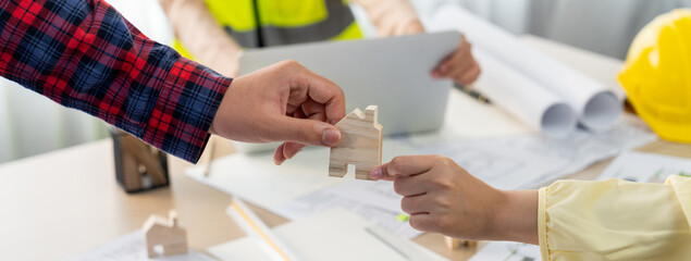 Professional engineer and architect collaborate on eco house project at meeting table with green...