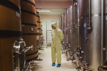 Winemaker working in modern large winery factory liquor drink industry quality. Staff inspecting wine in modern wine factory. Winery manufacturing quality control. Alcohol and wine winemaking process