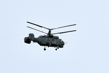 Russian military helicopter armed with missiles flies in blue sky, airborne mission of gunship with targeting system performs an aerial maneuvers for military operation, russian aviation