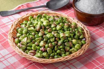 Caper buds in a basket and big sea salt on a table. Ready to be prepared for seasoning and pickles