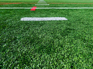 Sports Field Turf with Red and White Marker Lines. Bright green turf football or soccer field surface with white and red line markings. Overhead view.